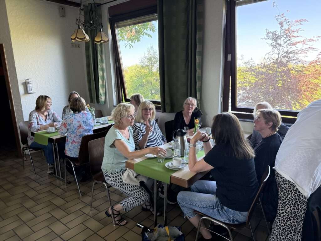 Menschen sitzen bei Kaffee und Kuchen zusammen